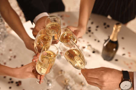 Friends clinking glasses of sparkling wine indoors, closeup. New Year celebrationの写真素材