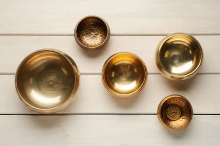 Golden singing bowls on white wooden table, flat layの写真素材