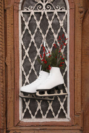 Pair of ice skates with Christmas decor hanging on old doorの写真素材