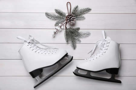 Pair of ice skates and Christmas decor on white wooden background, flat layの写真素材