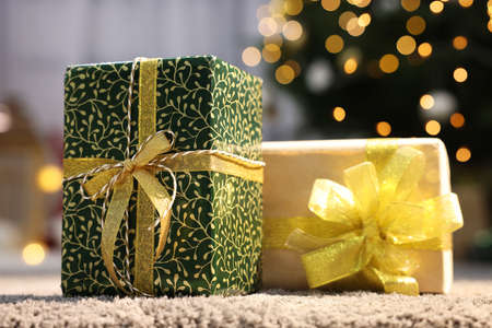 Beautiful Christmas gifts with golden bows on carpet indoorsの写真素材