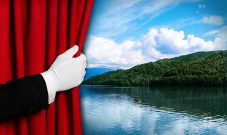 Man opening red front curtain and picturesque view of river and mountains on backgroundの写真素材
