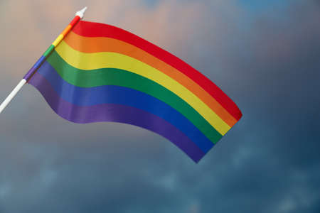 Bright rainbow LGBT flag against cloudy skyの写真素材