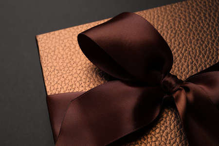 Brown gift box decorated with satin bow on black background, closeupの写真素材