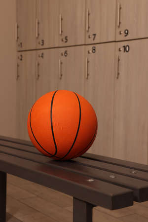 Orange basketball ball on wooden bench in locker roomの写真素材