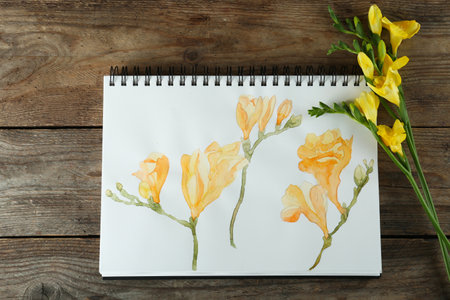 Beautiful drawing of freesia and flowers on wooden table, flat layの写真素材