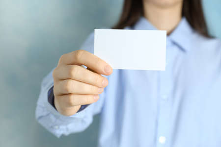 Woman holding blank business card on light blue background, closeup. Mockup for designの写真素材