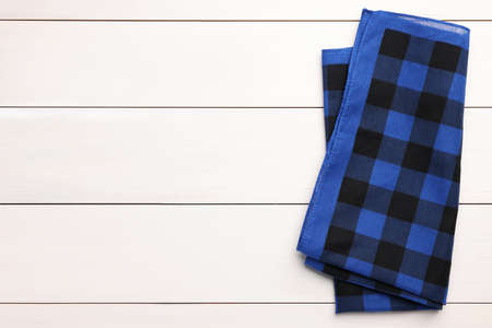 Folded blue checkered bandana on white wooden table, top view. Space for textの写真素材