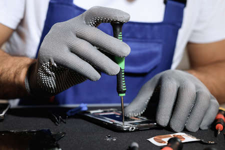 Technician repairing broken smartphone at table, closeupの写真素材