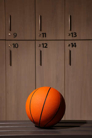 Orange basketball ball on wooden bench in locker roomの写真素材