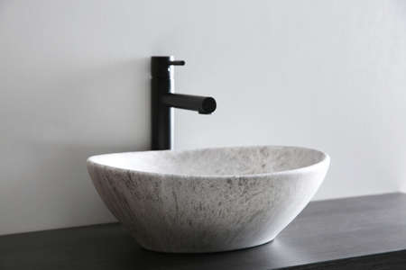 Stone vessel sink with faucet on wooden countertop