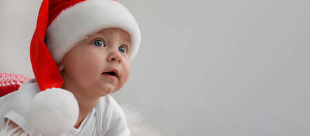 Cute baby wearing Santa hat on light gray background, banner design with space for text. Christmas celebrationの写真素材
