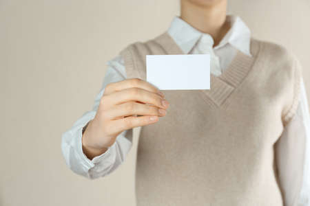 Woman holding white business card on beige background, closeupの写真素材