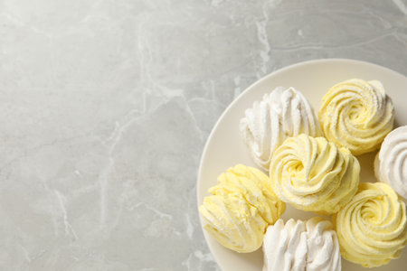 Delicious white and yellow marshmallows on gray marble table, top view. Space for textの写真素材