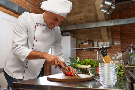 Professional chef cutting fresh tomato in restaurant kitchenの写真素材