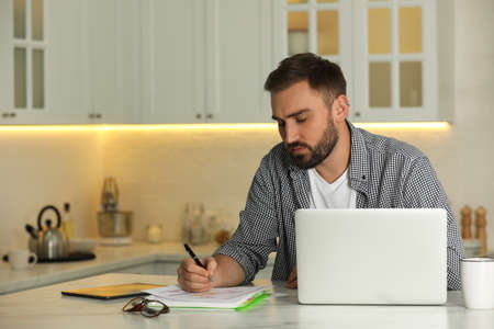 Young man working with laptop at home, space for textの写真素材