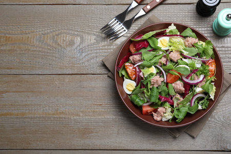 Bowl of delicious salad with canned tuna and vegetables served on wooden table, flat lay. Space for textの写真素材