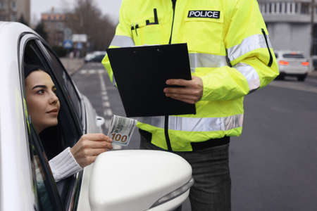 Woman giving bribe to police officer out of car window