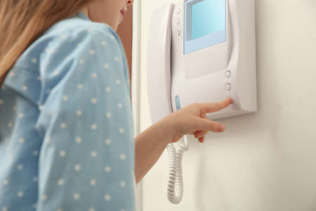 Cute little girl pressing button on intercom panel indoors, closeupの写真素材