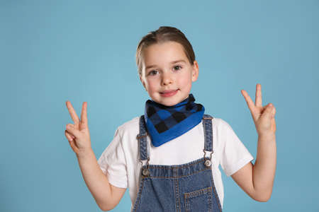Cute little girl wearing stylish bandana on turquoise backgroundの写真素材