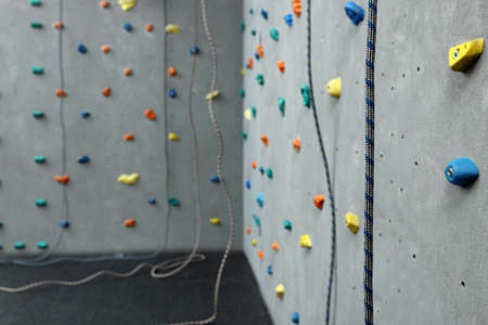 Climbing wall with holds and ropes in gym. Extreme sport