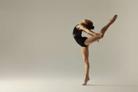 Cute little girl doing gymnastic exercise on white backgroundの写真素材