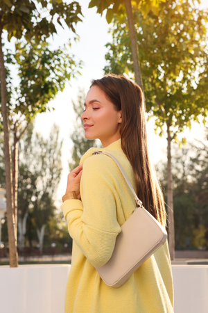 Fashionable young woman with stylish bag on city streetの写真素材