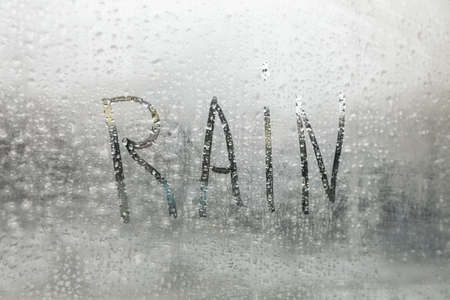 Word Rain written on foggy window, closeup viewの写真素材
