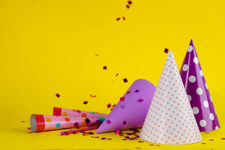 Colorful party hats and other festive items on yellow background. Space for textの写真素材