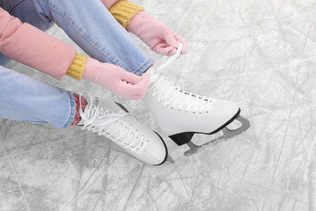 Woman lacing figure skates on ice, above viewの写真素材