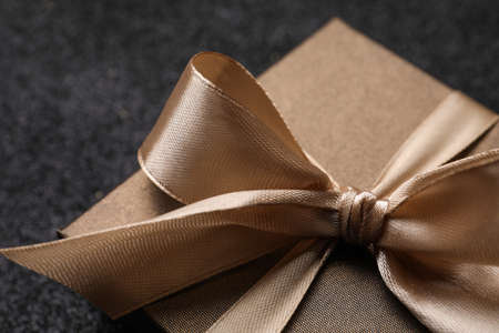 Shiny gift box with golden bow on black background, closeupの写真素材