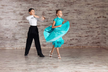 Beautifully dressed couple of kids dancing together in studioの写真素材
