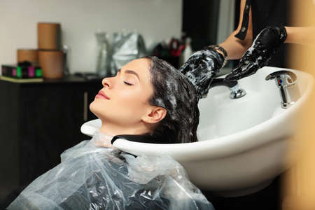 Hairdresser rinsing out dye from woman's hair in beauty salonの写真素材