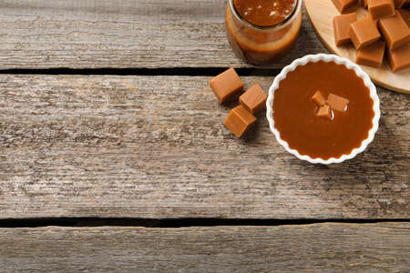 Tasty salted caramel and candies wooden table, flat lay. Space for textの写真素材