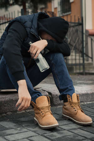 Addicted drunk man with alcoholic drink on stairs outdoorsの写真素材