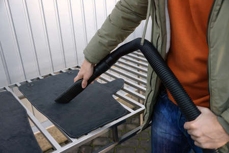 Man cleaning auto carpets with vacuum cleaner at self-service car wash, closeupの写真素材