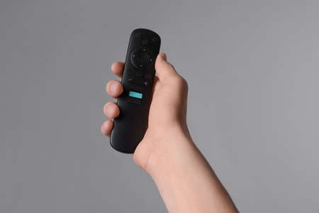 Woman holding TV remote control on gray background, closeupの写真素材