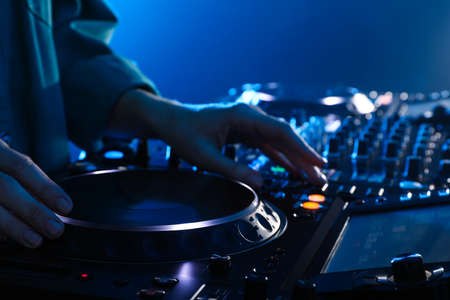 DJ creating music on modern console mixer in night club, closeup