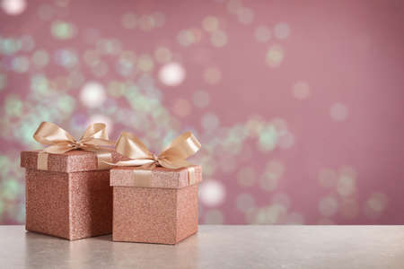 Beautiful gift boxes on white table against blurred festive lights, bokeh effect. Space for textの写真素材