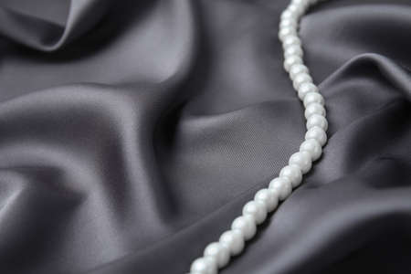 Beautiful pearls on gray silk, closeup. Space for textの写真素材