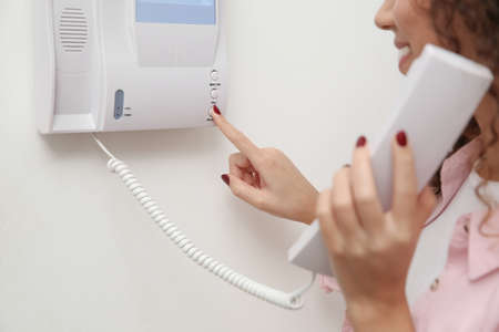 African-American woman pressing button on intercom panel indoors, closeupの写真素材