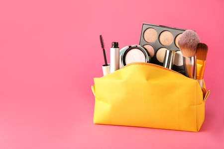Cosmetic bag with makeup products and accessories on pink background. Space for textの写真素材