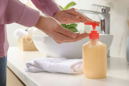 Woman using liquid soap dispenser in bathroom, closeupの写真素材