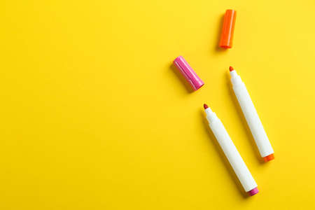 Colorful markers on yellow background, flat lay with space for text. School stationeryの写真素材