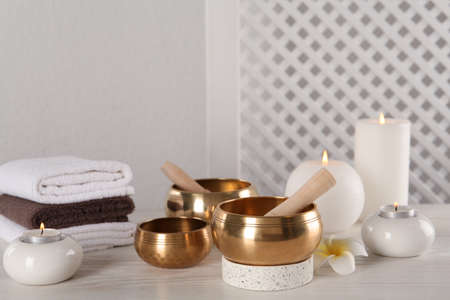 Composition with golden singing bowls on white wooden table