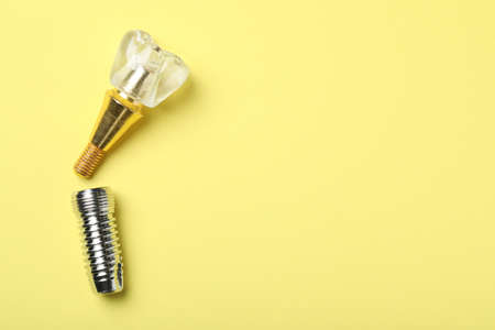 Parts of dental implant on yellow background, flat lay. Space for textの写真素材