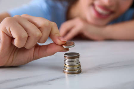 Young woman stacking coins at table, focus on hand. Money savingsの写真素材