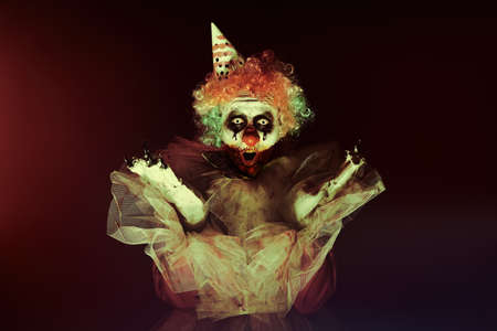 Terrifying clown in darkness. Halloween party costume