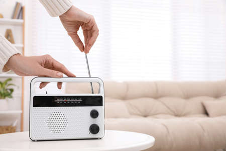Woman adjusting radio antenna at home, closeup. Space for text