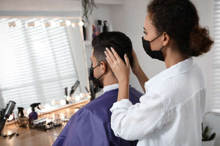 Professional stylist working with client in salon. Hairdressing services during quarantineの写真素材